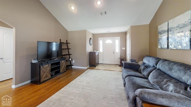 living room with visible vents, baseboards, vaulted ceiling, and wood finished floors