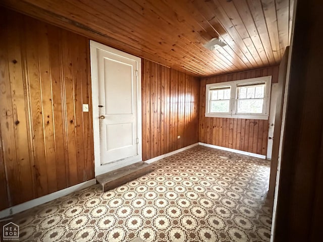 unfurnished room with wood walls, baseboards, and wooden ceiling