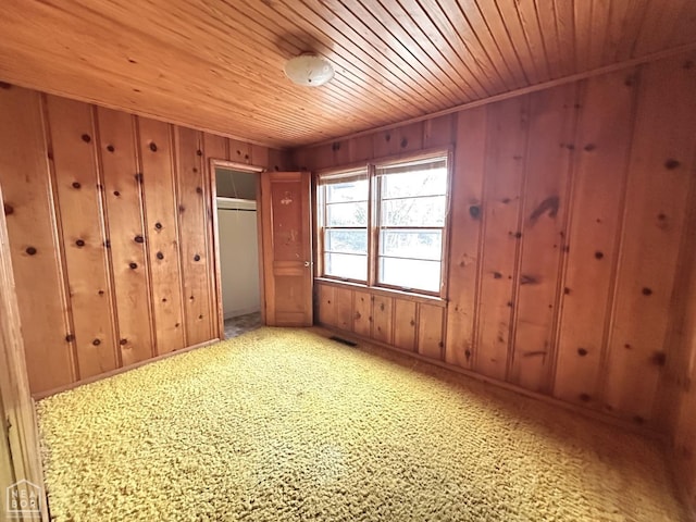 unfurnished bedroom with wooden walls, visible vents, wood ceiling, and baseboards