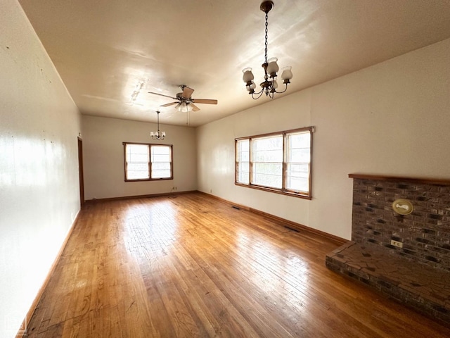 unfurnished living room with wood-type flooring, baseboards, and ceiling fan with notable chandelier