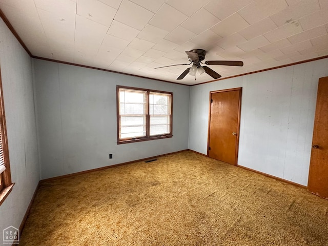unfurnished bedroom with baseboards, ornamental molding, carpet flooring, visible vents, and ceiling fan