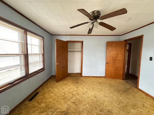 unfurnished bedroom featuring visible vents, baseboards, a closet, ornamental molding, and carpet