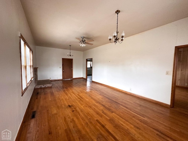 spare room featuring visible vents, baseboards, wood finished floors, and ceiling fan with notable chandelier