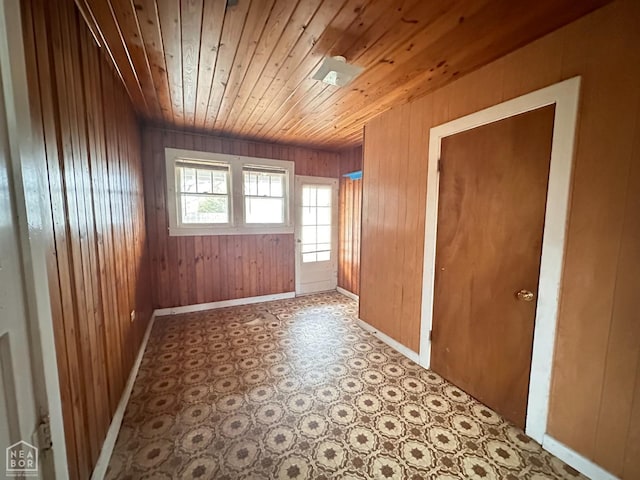 spare room featuring wooden walls, tile patterned floors, baseboards, and wooden ceiling