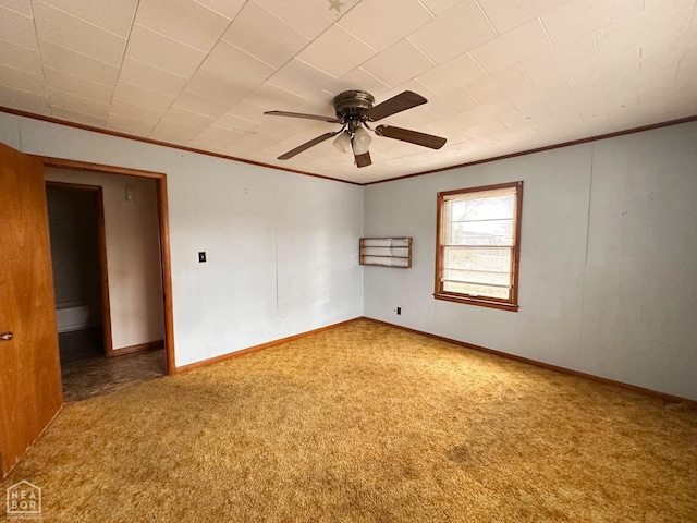 carpeted spare room featuring ceiling fan, baseboards, and ornamental molding