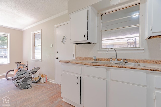 325 S 12th St, West Memphis, AR 72301 - kitchen with a sink, a textured ceiling, ornamental molding, light countertops, and light wood finished floors