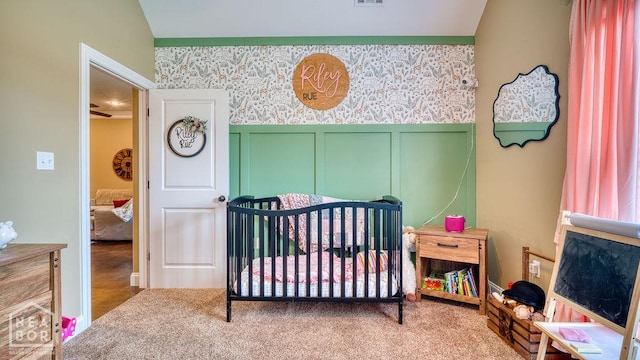 509 Wiregrass Way, Jonesboro, AR 72405 - bedroom with a crib, wallpapered walls, carpet floors, a wainscoted wall, and a decorative wall