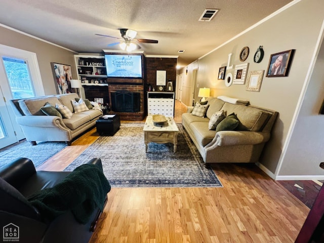 2804 Ivy Dr, Newport, AR 72112 - living room featuring crown molding, ceiling fan, a brick fireplace, wood finished floors, and a textured ceiling