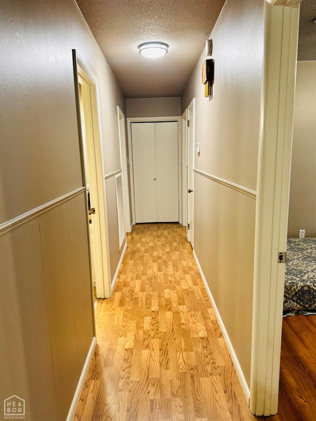 2804 Ivy Dr, Newport, AR 72112 - hallway with light wood-type flooring, a textured ceiling, and baseboards