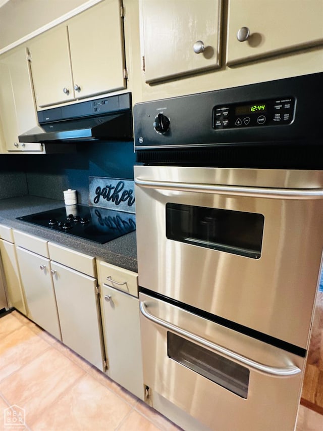 2804 Ivy Dr, Newport, AR 72112 - kitchen with under cabinet range hood, black electric cooktop, double oven, dark countertops, and light tile patterned floors