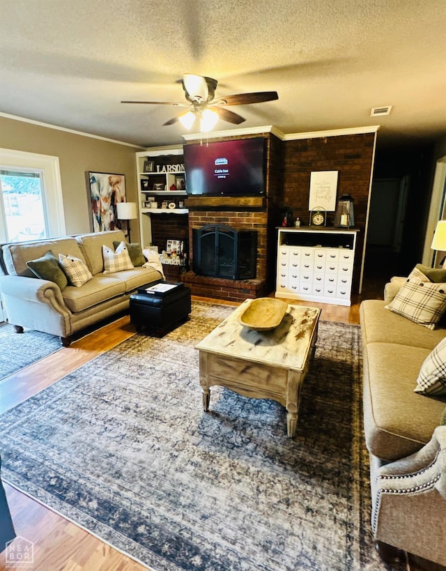 2804 Ivy Dr, Newport, AR 72112 - living room with ceiling fan, wood finished floors, crown molding, a textured ceiling, and a fireplace