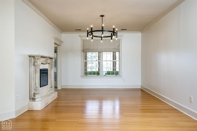 unfurnished living room featuring light wood finished floors, ornamental molding, and an inviting chandelier
