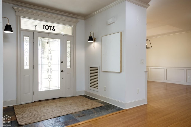 entrance foyer featuring wood finished floors, ornamental molding, visible vents, and plenty of natural light