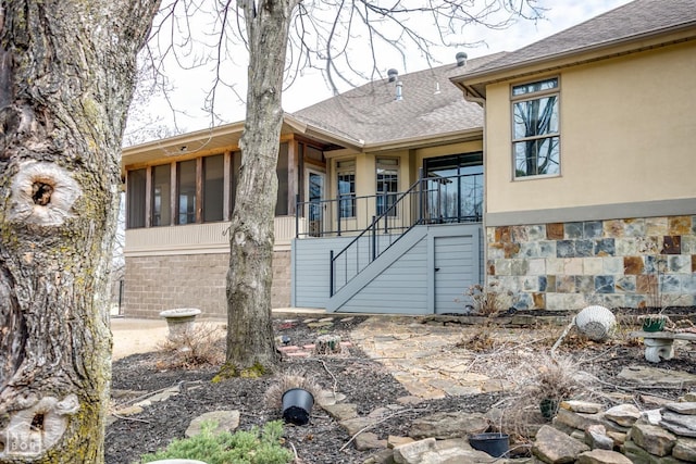 property entrance featuring a shingled roof, stucco siding, and stone siding