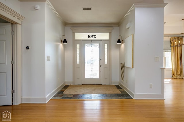foyer featuring an inviting chandelier, visible vents, crown molding, and wood finished floors