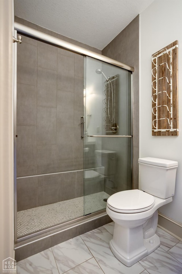 full bathroom with a shower stall, marble finish floor, a textured ceiling, and toilet