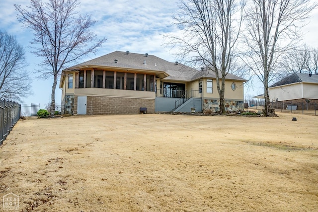rear view of property featuring a shingled roof, fence, a sunroom, and stairway