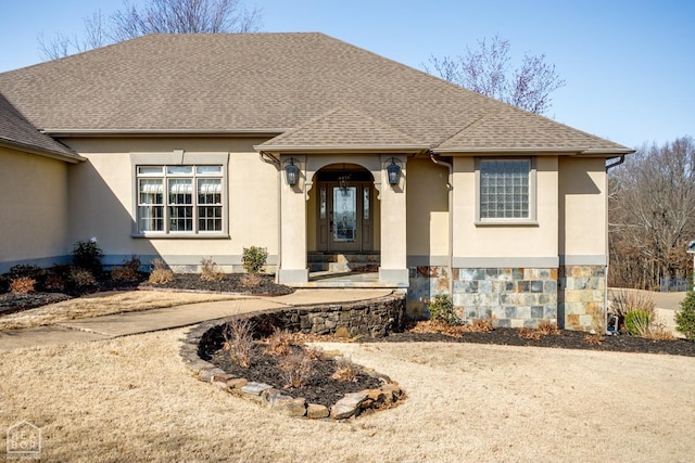 view of front of home with roof with shingles, stucco siding, and stone siding
