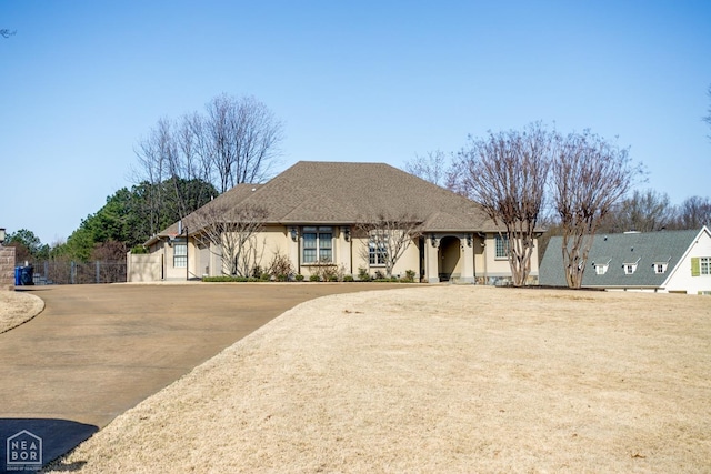 view of front of property with fence, driveway, and stucco siding