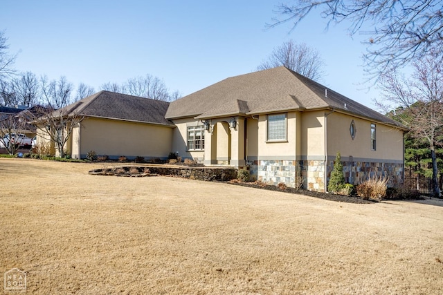 view of front of house with a shingled roof, stone siding, and stucco siding