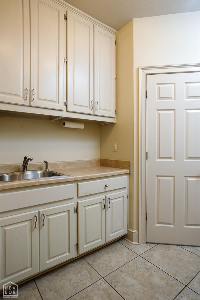 kitchen featuring light countertops, light tile patterned floors, a sink, and white cabinets