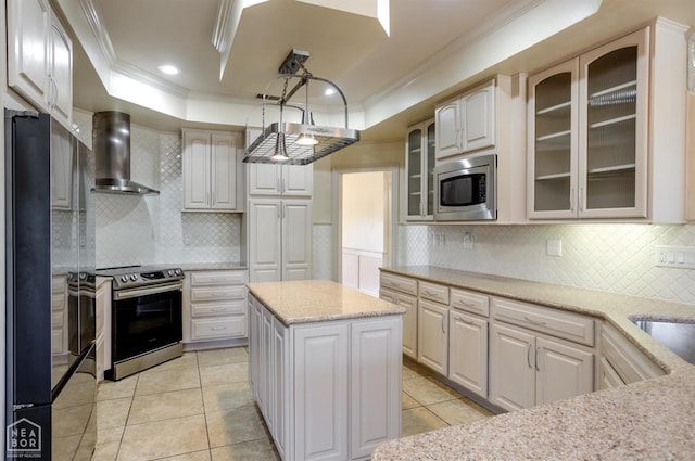 kitchen with light tile patterned floors, a tray ceiling, wall chimney range hood, ornamental molding, and stainless steel appliances