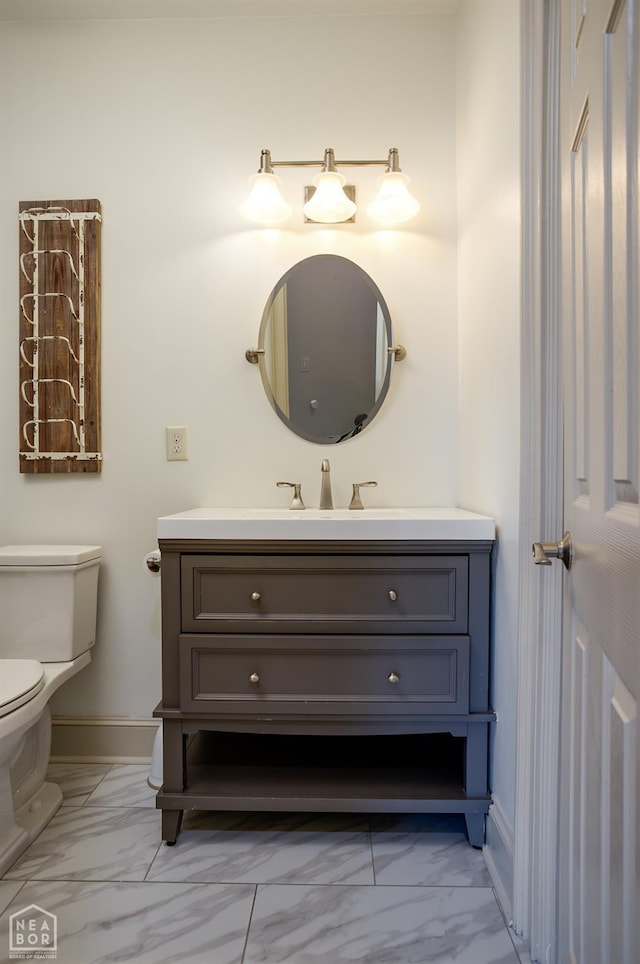 half bathroom featuring vanity, marble finish floor, baseboards, and toilet