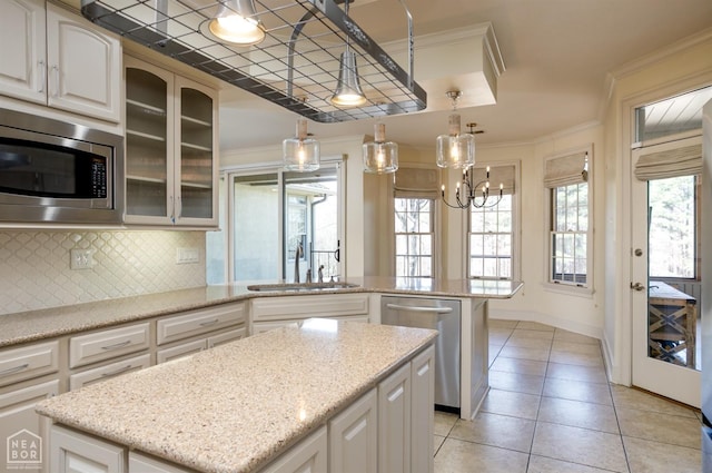 kitchen featuring appliances with stainless steel finishes, a center island, crown molding, decorative backsplash, and a sink
