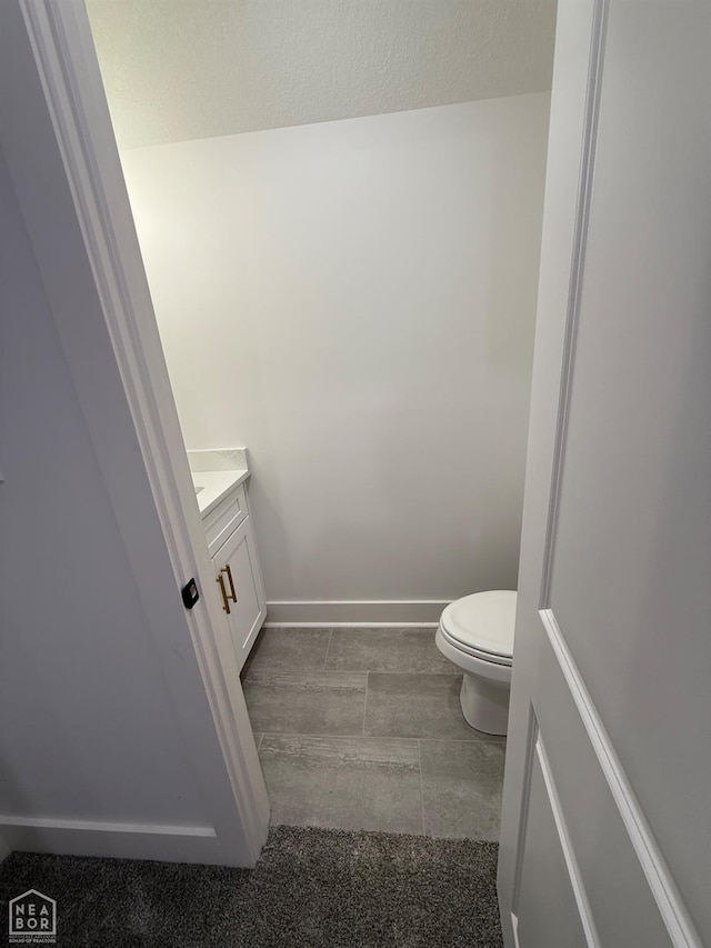bathroom featuring toilet, vanity, and baseboards