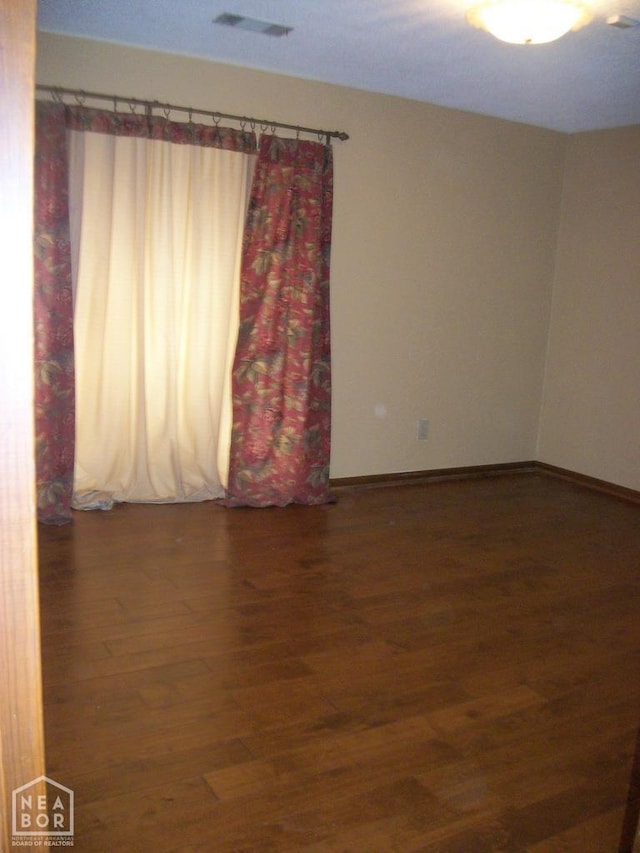 unfurnished room with visible vents, baseboards, and wood finished floors