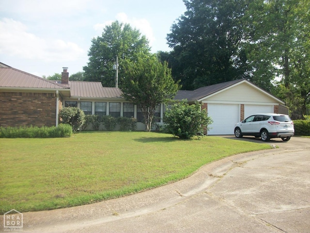 single story home with concrete driveway, a chimney, a front yard, brick siding, and a garage