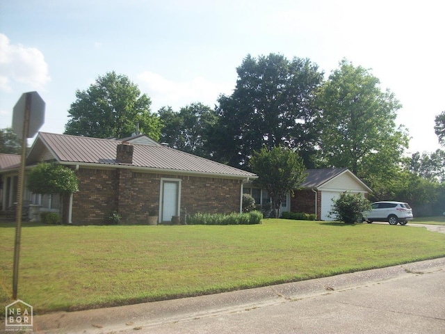 view of front of house featuring a front yard, brick siding, an attached garage, and metal roof