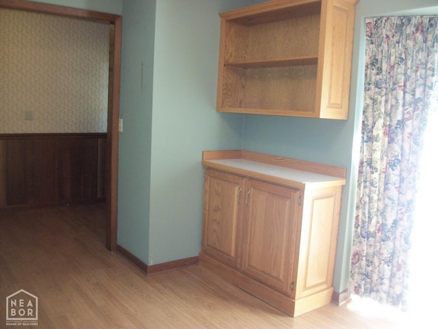 interior space featuring light wood-type flooring, light countertops, baseboards, and open shelves