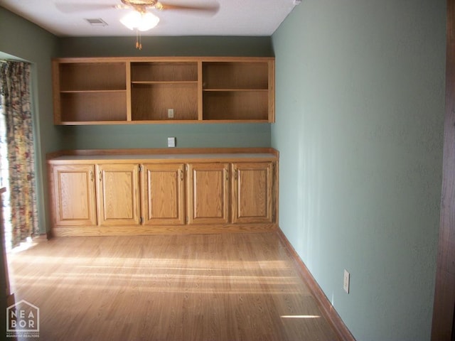unfurnished office featuring visible vents, ceiling fan, light wood-style floors, and baseboards