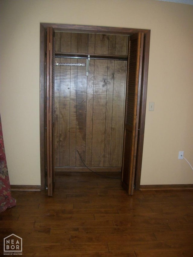 hallway featuring baseboards and dark wood-style floors