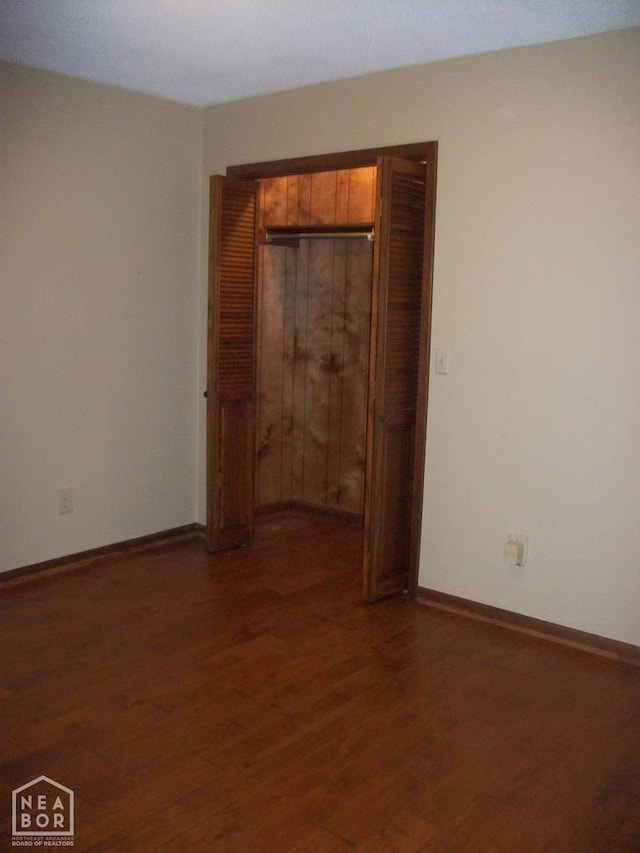 unfurnished bedroom with a closet, baseboards, and wood finished floors