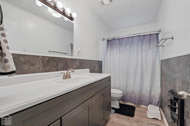 208 S Rockingchair Rd, Paragould, AR 72450 - full bath with wood finished floors, toilet, vanity, tile walls, and wainscoting