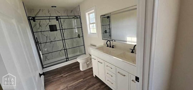 bathroom with toilet, wood finished floors, vanity, and a stall shower
