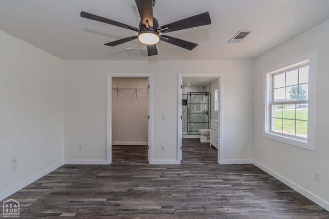 unfurnished bedroom with a walk in closet, baseboards, visible vents, and dark wood-style floors