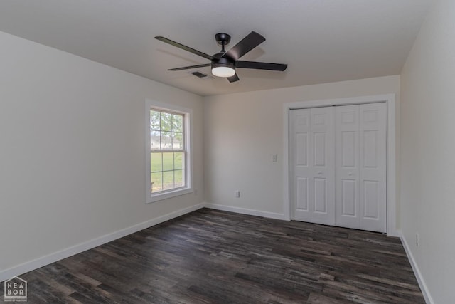 unfurnished bedroom featuring dark wood finished floors, baseboards, visible vents, and a closet