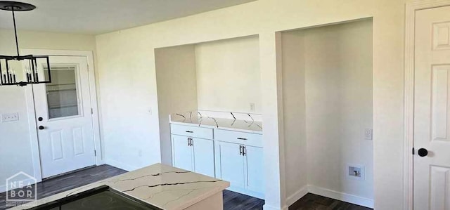 laundry area with dark wood-type flooring and baseboards