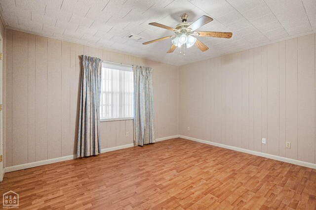 1303 Magnolia Ave, Walnut Ridge, AR 72476 - spare room with wooden walls, visible vents, light wood finished floors, and a ceiling fan