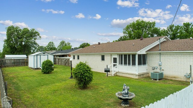 1303 Magnolia Ave, Walnut Ridge, AR 72476 - rear view of property featuring a fenced backyard, brick siding, a lawn, a sunroom, and a shed