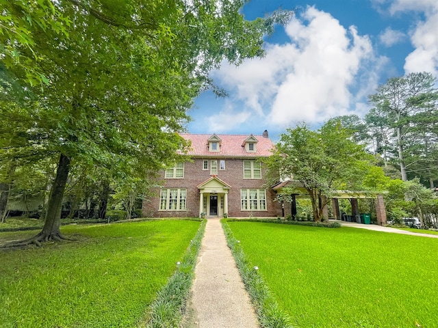 view of front of home with a front yard, brick siding, and a chimney