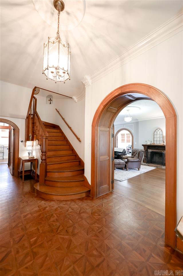 foyer with dark parquet floors, crown molding, and an inviting chandelier