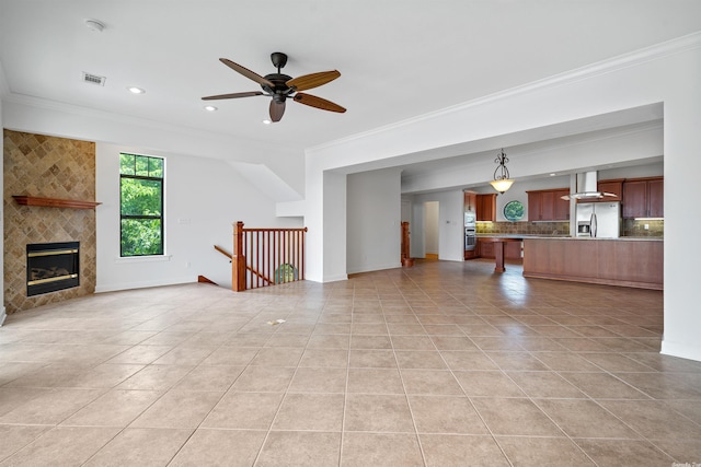 unfurnished living room with a tiled fireplace, ornamental molding, ceiling fan, and light tile floors