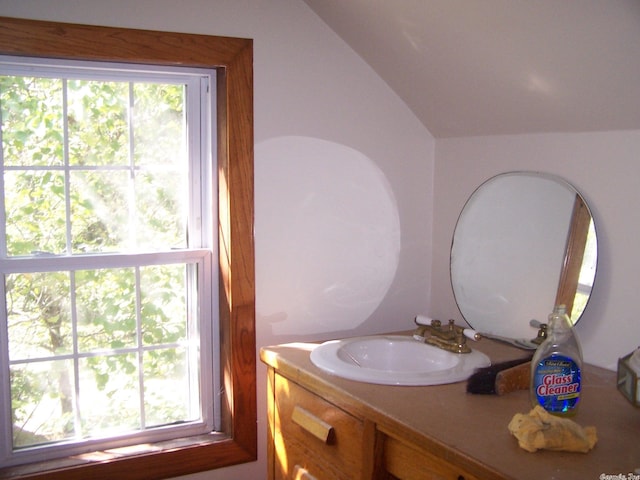 bathroom with lofted ceiling, a healthy amount of sunlight, and large vanity