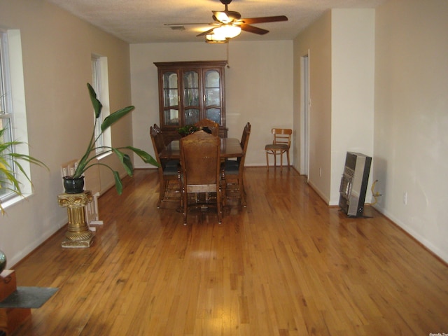 dining area with light hardwood / wood-style flooring, heating unit, ceiling fan, and a textured ceiling