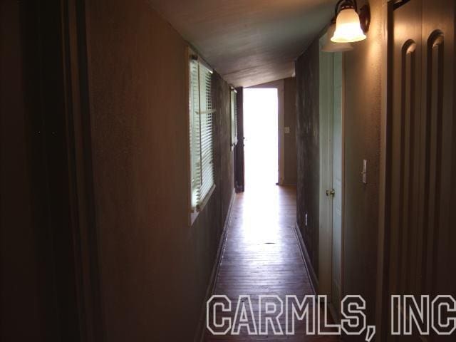 hall featuring dark wood-type flooring and vaulted ceiling