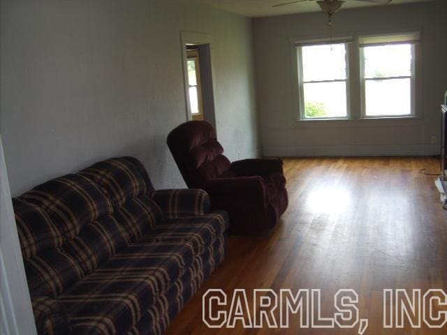 living room with ceiling fan and dark wood-type flooring